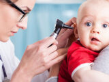تصویری از پزشک در حال سنجش شنوایی یک کودک